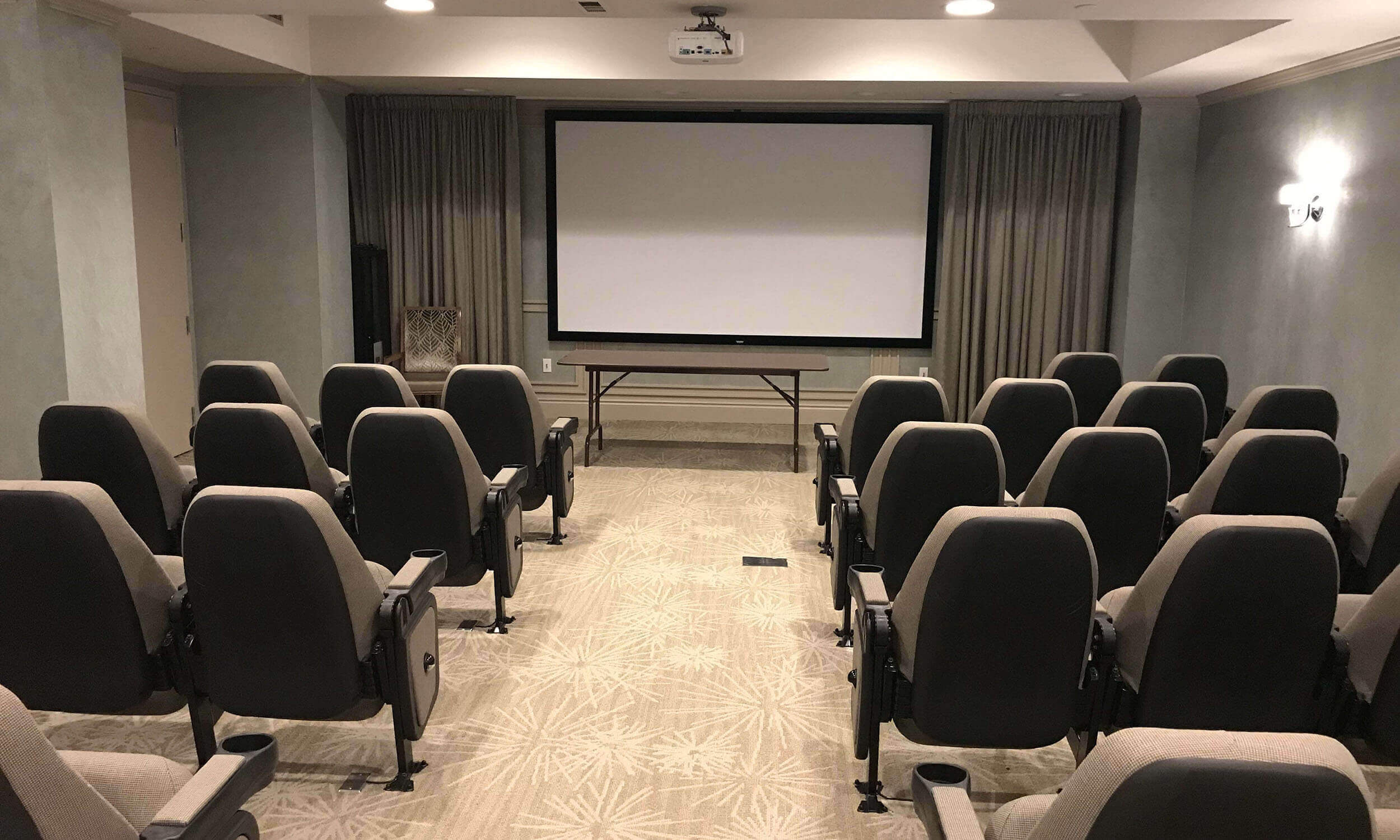 Entertainment room of retirement home with large movie screen and rows of seating