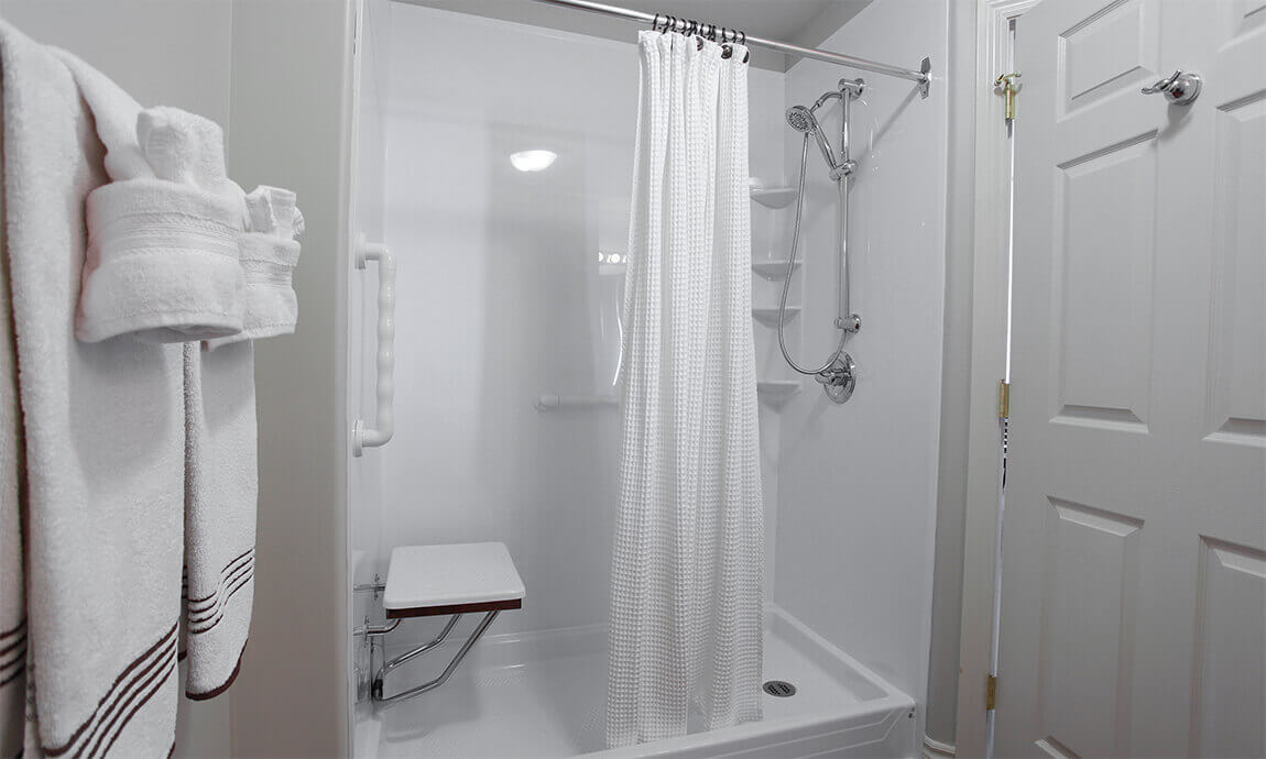 Accessible bathroom shower with handrails and a seat. 