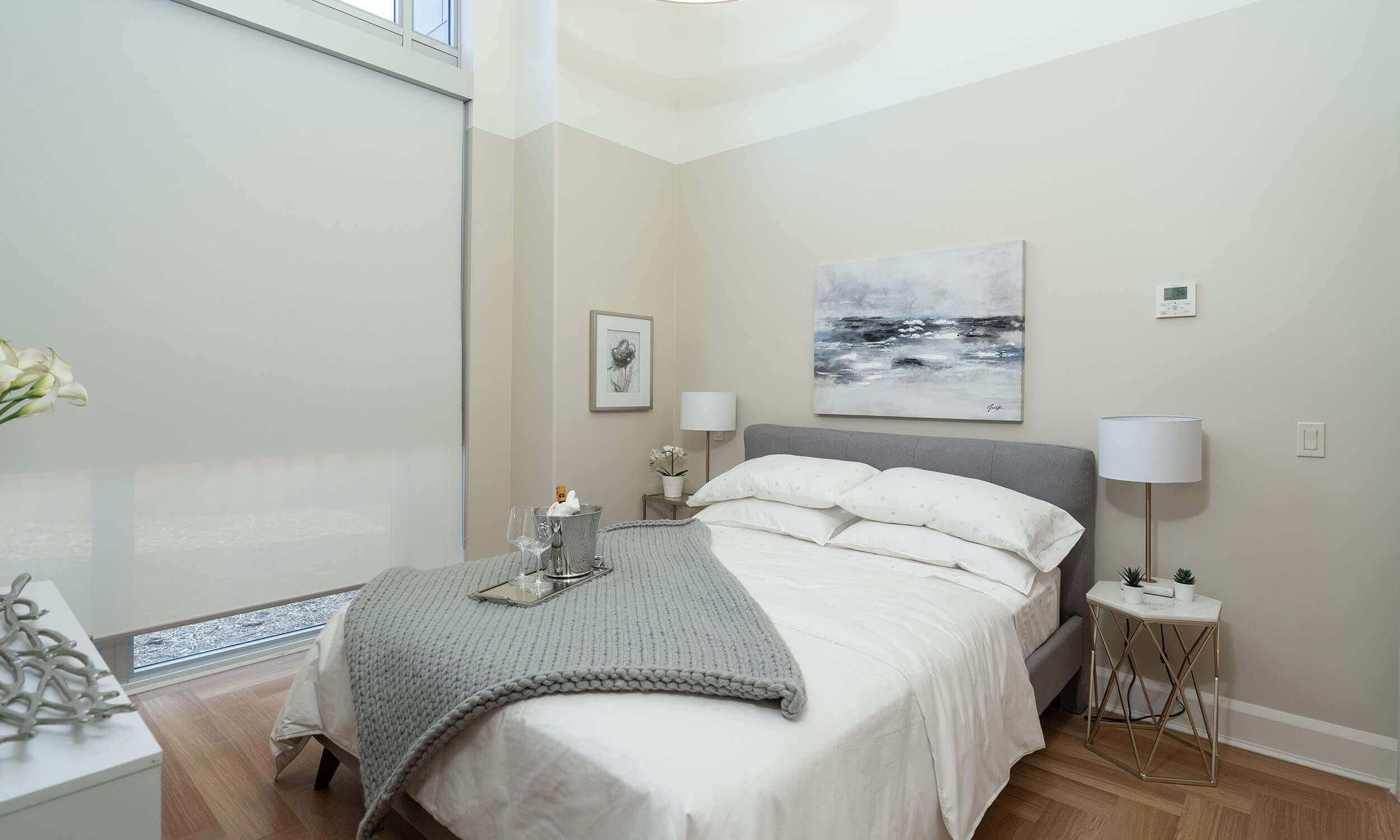 White bedroom in Parkland residence with grey accents, two side tables with lamps, and large window
