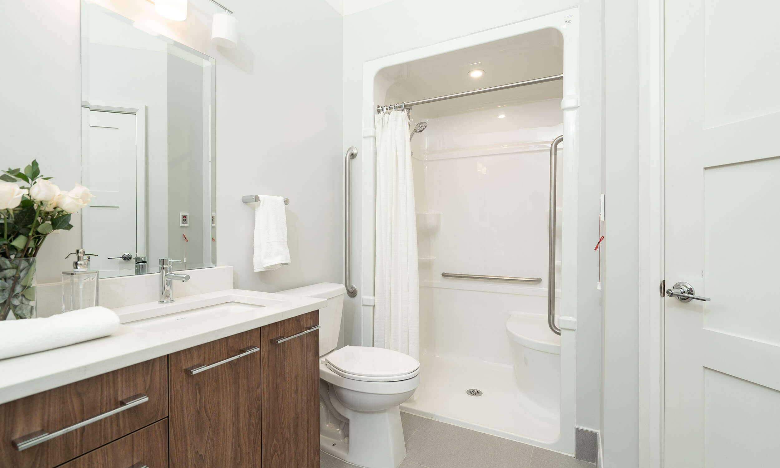 White washroom in Parkland suite with white and wood vanity, toilet, and spacious shower