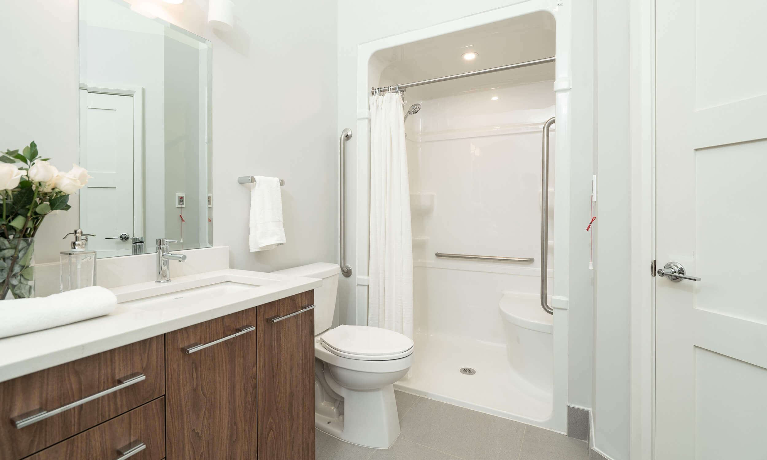 White washroom in Parkland suite with white and wood vanity, toilet, and spacious shower