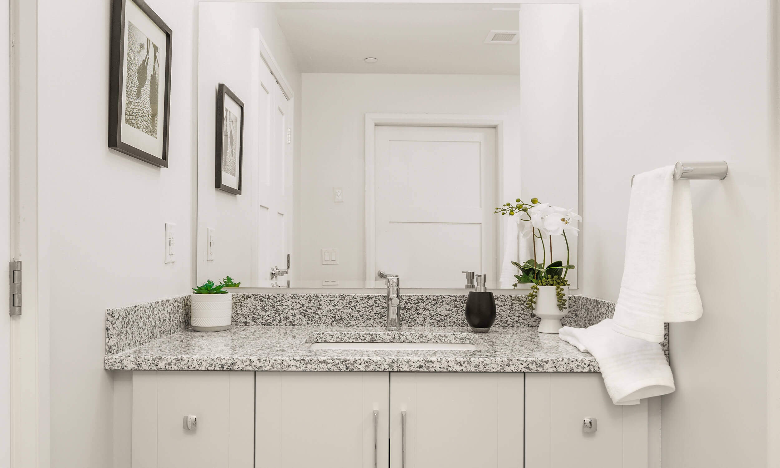 Modern-looking white vanity with grey granite countertop