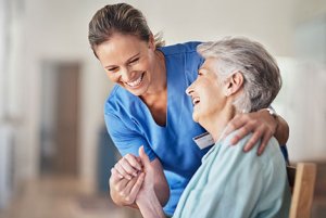 Nurse in blue scrubs smiling and assisting retirement home resident