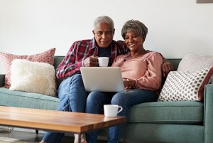 Senior couple sitting on couch and looking at laptop together