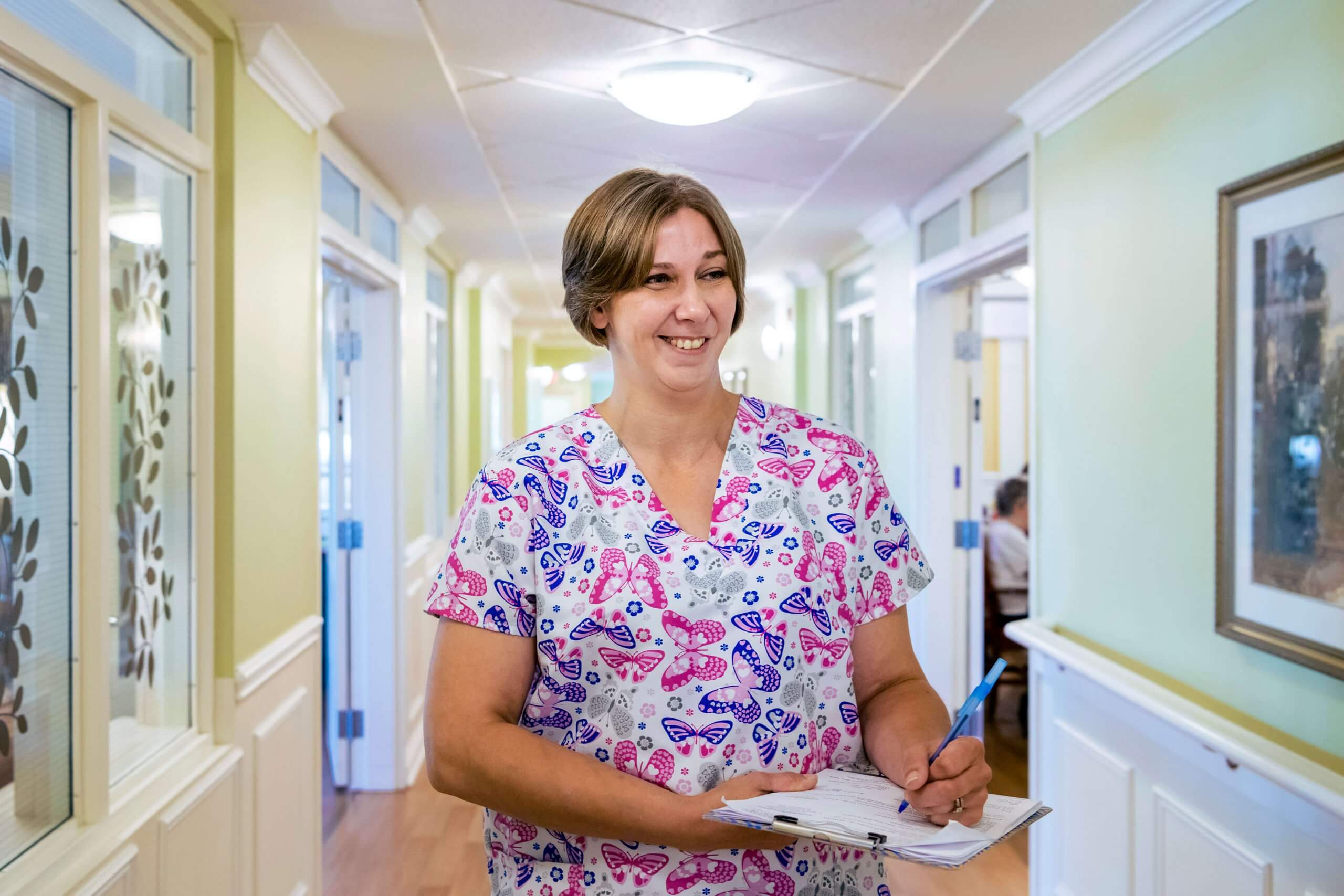 Retirement nurse wearing floral scubs in Parkland facility collecting data on clipboard
