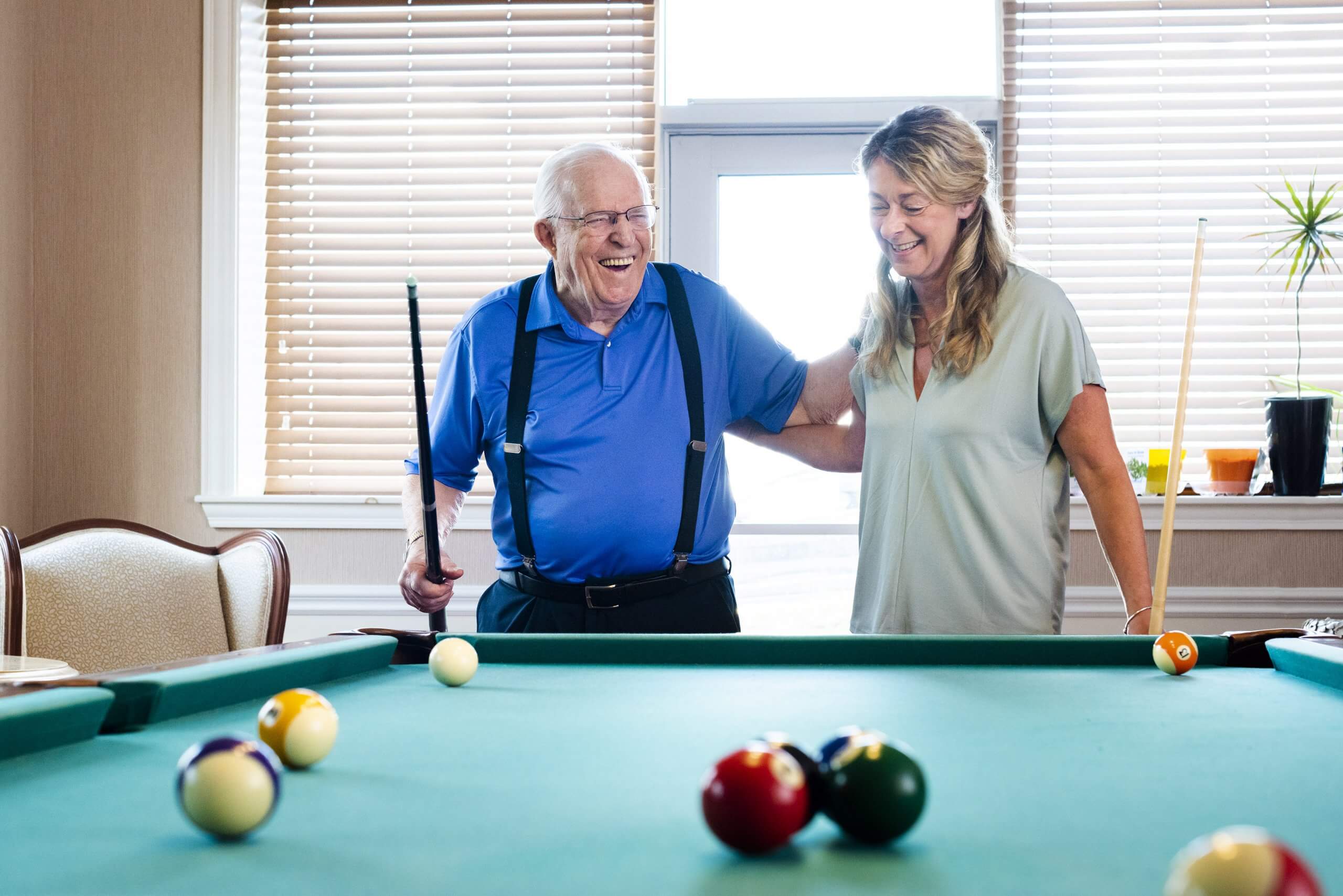 Man and woman standing and laughing over game of pool