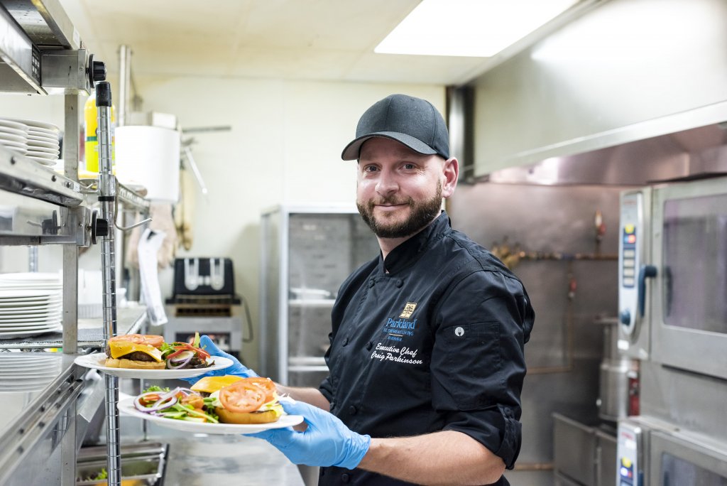 Parkland executive chef presenting two hamburger meals in kitchen