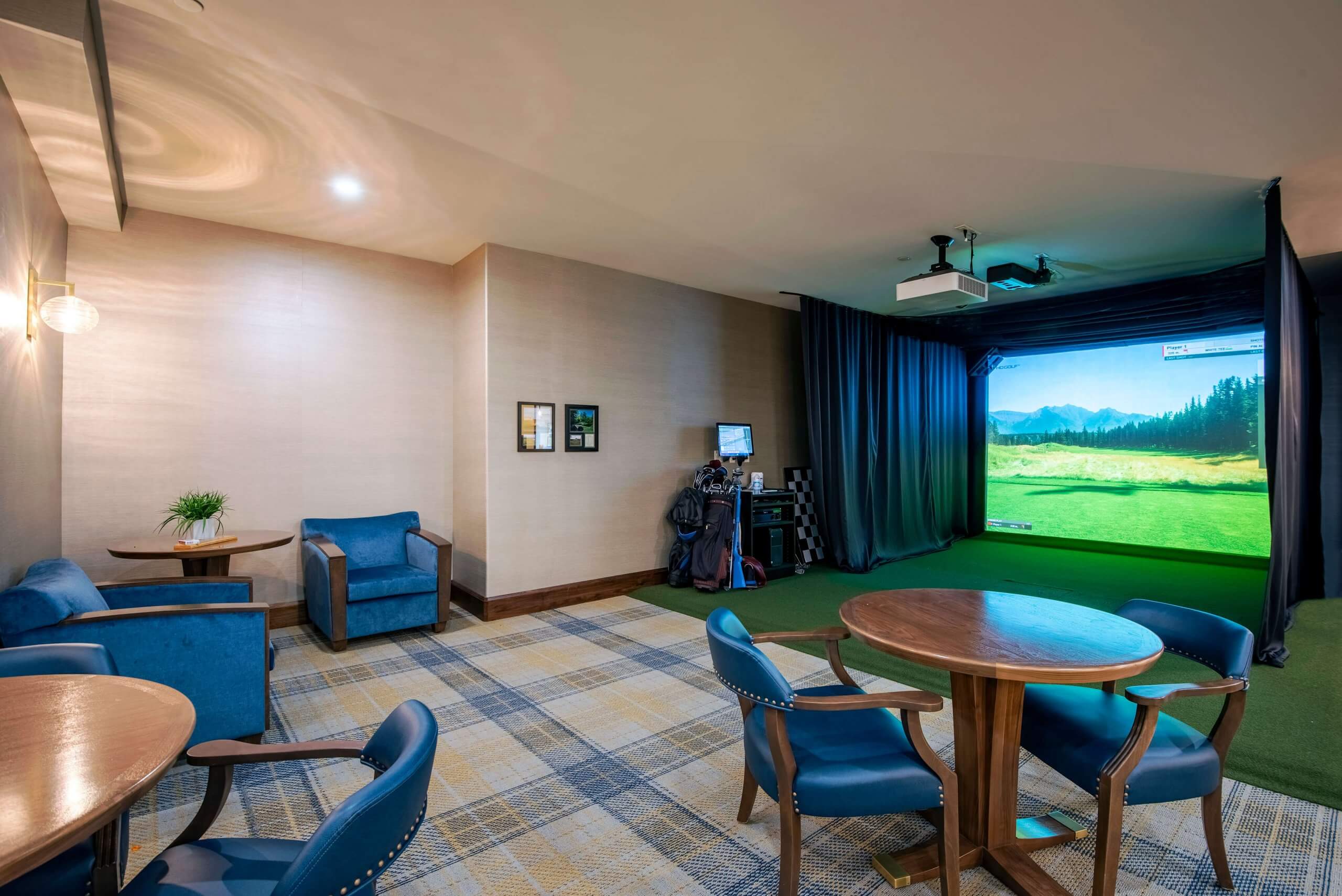 Activity room in retirement home with virtual reality golf displayed on large screen next to equipment, and three tables with chairs