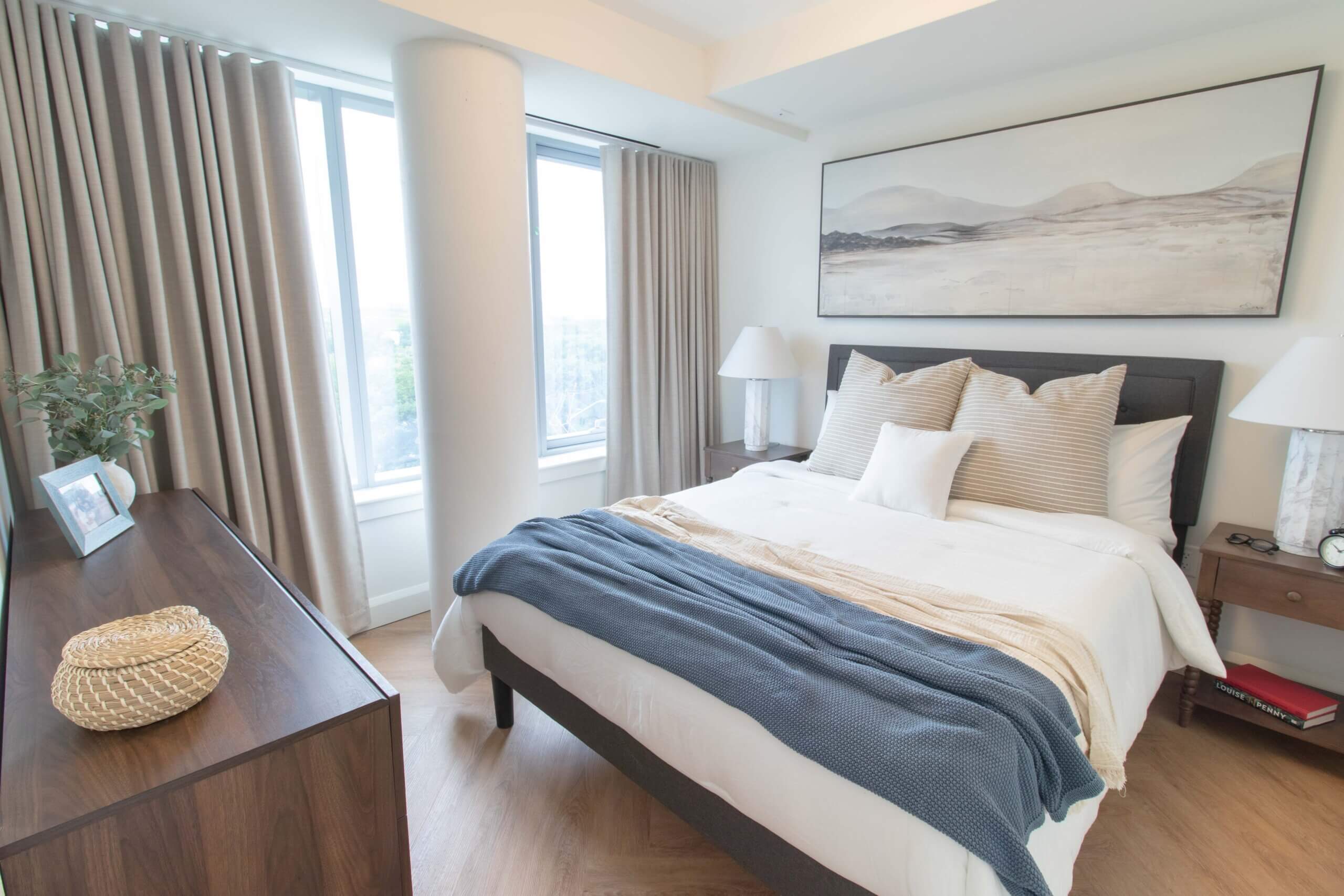 A bright room with a bed curtains and dresser.
