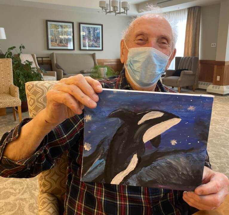 Resident, Frank Robinson holding up a painting of a whale. 